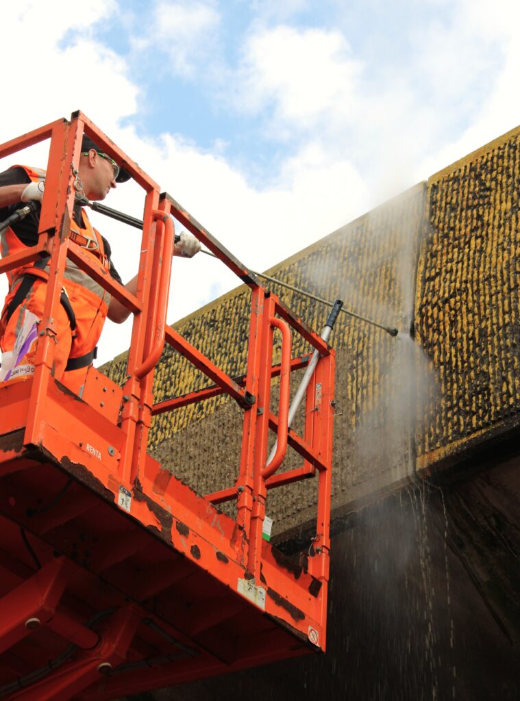 Medewerker van Topcoat reinigt een viaduct vanaf een hoogwerker