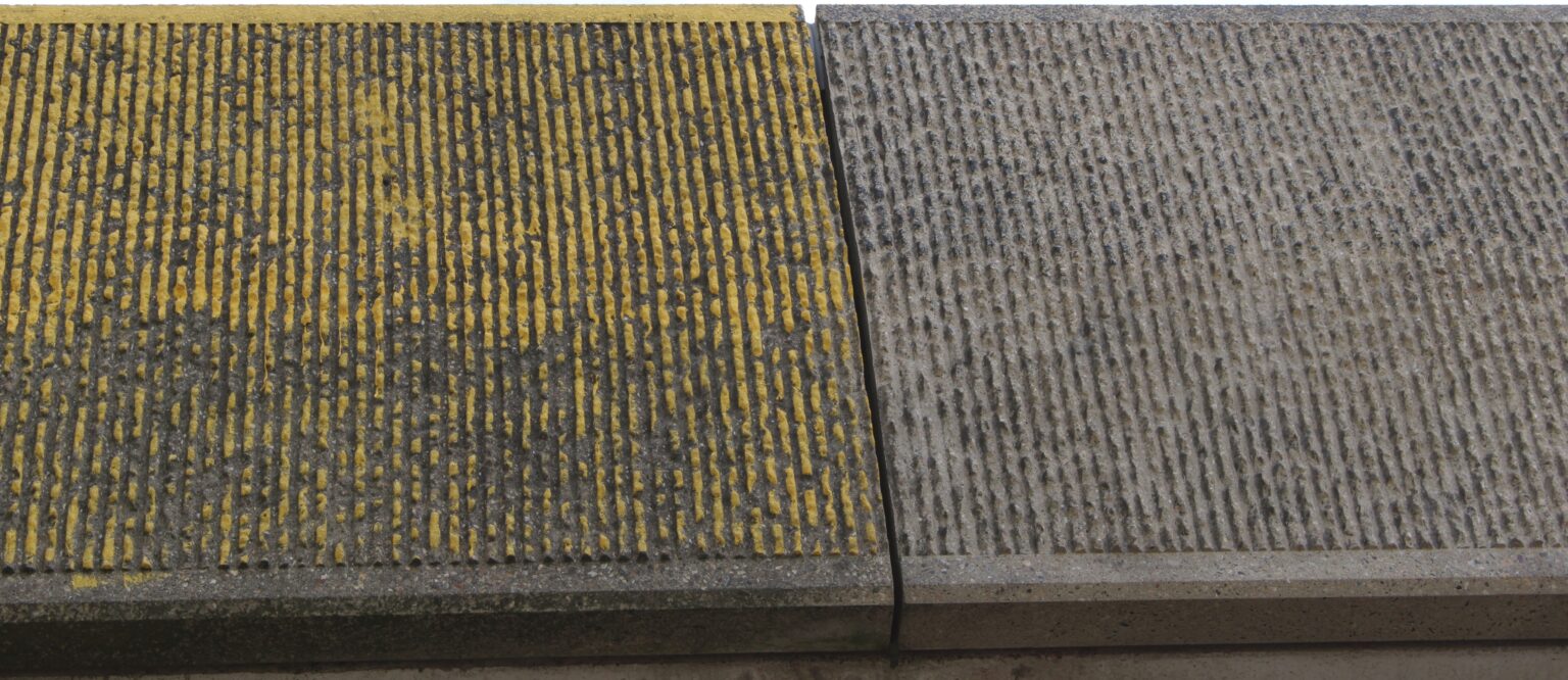 Betonnen rand met graffiti naast een gereinigd deel: het verschil voor en na